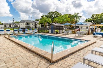 A large outdoor swimming pool surrounded by a brick patio.